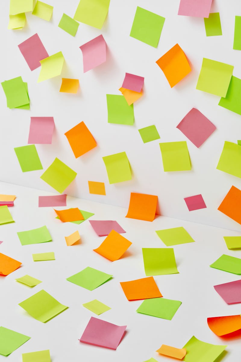 A vibrant display of scattered sticky notes in various colors on a white surface.